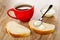 Cup with tea, spoon on slice of bread, sandwich with condensed milk on table