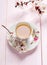 Cup of tea and spring flowers blooms of an Apricot on a light pink wooden table