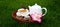 a cup of tea and a teapot on a wooden stand with a jar of honey and pink flowers