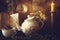 Cup of Tea and Teapot on wooden table with vintage clock, burning candle and old book