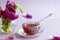 A cup of tea with a teaspoon on the background of a bouquet of lilac tulips, side view, close-up, space for text