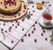 Cup of tea with thyme and honey pancakes with berries lingonberry on wooden rustic background top view close up