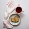 Cup of tea and two slices of sponge cake in a plate on a white table with a white and red tea towel. Top view.