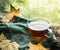 Cup of tea on a wooden rain window sill with a green cloth and autumn leaves on a natural background