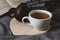 Cup of tean and teapot on wooden heart book and scarf on background