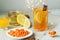 Cup of vitamin anti-cold tea with lemon slices, sea buckthorn berries and cinnamon with festive garland on wall and ingredients on