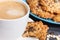 Cup of white coffee and fresh baked oatmeal cookies with honey and healthy seeds. Delicious crunchy dessert