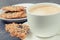 Cup of white coffee and fresh baked oatmeal cookies with honey and healthy seeds on plate. Delicious crunchy dessert