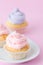 Cupcake decorated with pink and violet buttercream on pastel pink background. Sweet beautiful cake. Vertical banner, greeting card