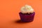 Cupcake in purple wrap on coral colour background. Minimal. Copy space