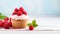 Cupcake with rasberries on white wooden table over light blue background. Cupcake banner, copy space. Vanilla raspberry cupcake