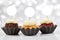 Cupcake Toppers Mockup with Three Gourmet Cupcakes and a Bokeh Patterned Background