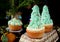 Cupcakes decorated as Christmas fir trees on a wicker basket surrounded by festive attributes