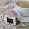 Cupcakes decorated with cream flowers: rose on wooden background with a lacy napkin with cup of coffee. Piece of cupcake.