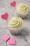 cupcakes with pink hearts on a gray concrete table copy space