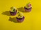 Cupcakes in purple wrap on solid yellow background with strong shadow. Pop art. Trendy funky minimalist style. Food fashion poster