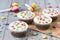 Cupcakes with white icing and coloured smarties, party horns and confetti, wooden background