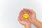 Cupped hands holding a yellow smiling face on a white background. Be positive and share happiness concepts