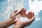 Cupped hands partially submerged in clear blue drinking water - Wet hands raised from a fresh water spring