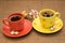 Cups of coffee with colorful candies and glass bowl between them