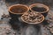 Cups of coffee among selected and calibrated Arabica coffee beans scattered on a black background.