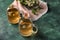 Cups of delicious camomile tea on green table