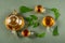 Cups of herbal tea, transparent teapot and nettle leaves on green background. Top view Flat lay