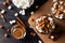 Cups with hot chocolate and marshmallows on cutting board between cinnamon, top view