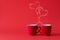 Cups of tea or coffee with steam in two heart shape on red background. Valentine`s day celebration or love concept. Copy space