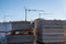 Curbs on several pallets, three cranes in background, blue sky