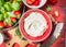 Curd or cream cheese in red bowl with strawberries, close up