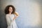 Cure curly hair girl eating croissant against wall