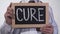 Cure written on blackboard in therapist hands, innovative treatment method