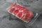 Cured ham jamon vacuum plastic pack, on gray stone table background, with copy space for text