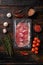 Cured ham jamon vacuum plastic pack, on old dark  wooden table background, top view flat lay