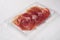 Cured ham jamon vacuum plastic pack, on white stone table background, with copy space for text