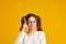 Curious Asian girl is thinking and standing on yellow background with curious face, blank copy space for your advertising content