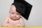 Curious baby in academic hat at the table. Educational concept