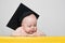 Curious baby in academic hat at the table. Educational concept