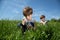 Curious Boy With Magnifying Glass Exploring White Daisy On Green Field At Spring Time