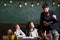 Curious cheerful children listening teacher with attention. Teacher and girls pupils in classroom, chalkboard on