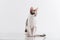 Curious Cornish Rex Cat Stand on the White Table. White Wall Background. Long Tail.