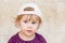 Curious cute blond baby girl in white baseball cap
