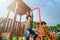 Curious fearless little girl climbing on playground alone in sunny weather