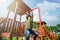 Curious fearless little girl climbing on playground alone in sunny weather