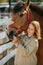 Curious ginger girl holding horse`s snout, touching horse`s head with hers