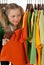 Curious girl looking out of the clothes rack