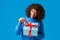 Curious and happy, smiling african-american woman, b-day girl in winter sweater, pulling present knot to unwrap gift and