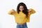 Curious and intrigued cute feminine african american girl in yellow sweater pointing and looking down with amused smile