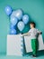 Curious kid boy looks at pastel color blue balloons for birthday party flying out of white box he has just opened